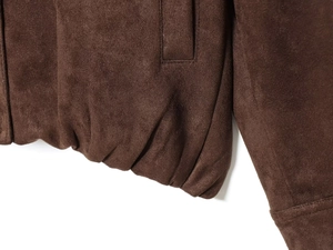 Detailed close-up of brown faux suede jacket featuring elastic hem and fine stitching details