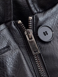 Macro shot of black PU leather texture with metal zipper and four-hole resin button detail