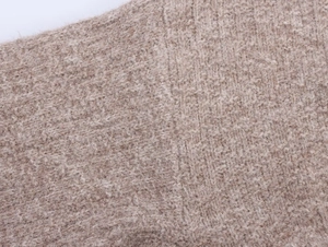 Close-up of beige knit cardigan fabric texture with soft wool-like feel and warmth