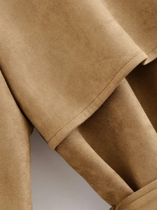 Detailed close-up of camel suede fabric texture and neat stitching on a double-breasted trench coat