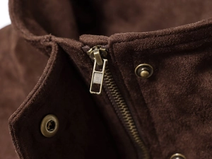 Detail of vintage bronze zipper and premium brown suede texture on the jacket