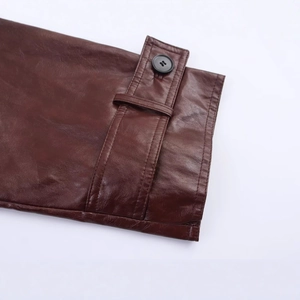 Detail of dark brown PU leather jacket sleeve with buttoned cuff and neat stitching