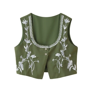 Detail of dark green vest with white floral embroidery and shiny silver sequins