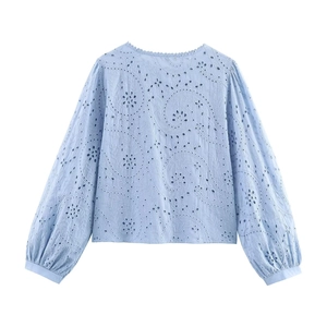 Detailed view of light blue eyelet embroidered shirt with floral lace and scroll pattern