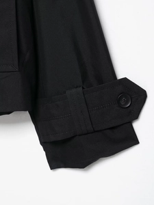 Détail du poignet de trench imperméable avec boucle noire et texture en sergé