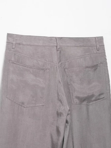 Detail view of grey trousers featuring large back patch pockets and fine twill texture