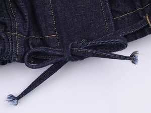 Gros plan détaillé du denim bleu foncé avec coutures jaunes et cordons effilochés