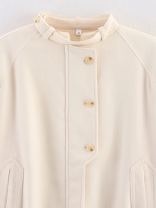 Detail of warm beige jacket featuring tortoiseshell buttons and stand collar