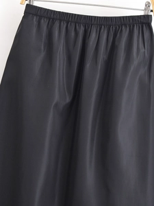 Detailansicht eines schwarzen Satin-Minirocks mit elastischem Kordelzug am Bund und Glanzeffekt