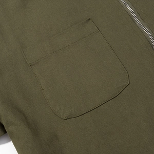 Detail of army green jacket showing twill fabric texture, flat pocket, and silver zipper