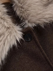 Close-up of luxury dark brown wool coat featuring a plush faux fur collar and button detail