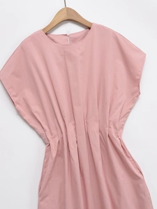 Detail of pink summer dress featuring waist pleats and teardrop neckline slit