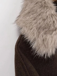 Close-up of fluffy faux fur collar and textured wool blend fabric on brown coat