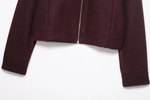 Detail of burgundy wool-like cropped jacket featuring metal zipper and ribbed hem