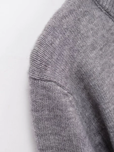 Detail of gray knit cardigan showing shoulder seam stitching and soft wool texture