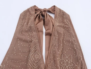 Detail of sequined mesh fabric with halter neck bow tie on a brown cropped top