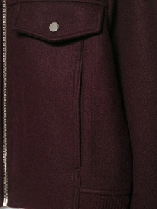 Close-up of burgundy wool jacket featuring silver zipper, snap pockets and ribbed hem
