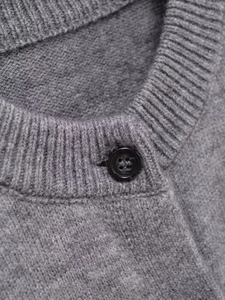 Macro detail of the grey knit cardigan showing the ribbed crew neck and black button