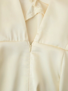 Détail de la fermeture éclair invisible sur une robe en satin crème à col en V chic