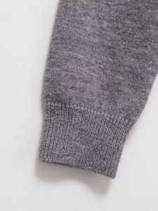Close-up of dark grey knitted cardigan cuff showing high-quality wool texture and ribbed hem