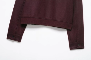Detail of burgundy baseball jacket featuring ribbed hem and metal snap button on cuff