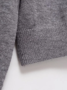 Close-up of grey wool knit cardigan showing fine texture and ribbed cuff detail