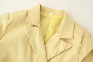 Detailed close-up of peak lapels and twill texture on a light yellow blazer