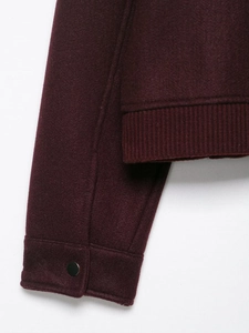 Detail view of burgundy soft jacket with ribbed hem and shiny black cuff button