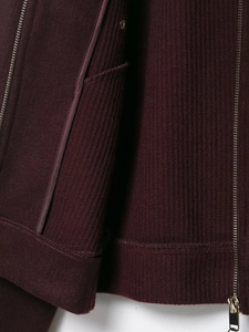 Detail of dark purple jacket featuring ribbed cuffs, metal zipper and snap button pockets