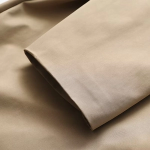 Detailed macro view of khaki trench coat sleeve hem showcasing premium stitching and fabric