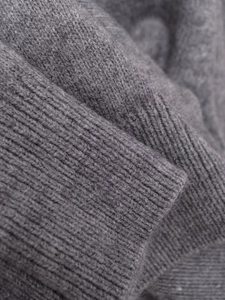 Close-up of ribbed cuffs and soft dark grey wool texture on knit cardigan