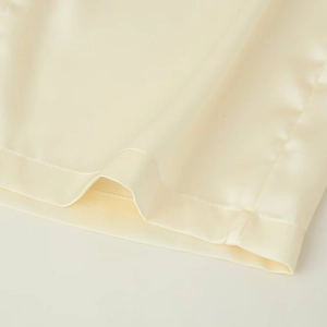 Robe col en V en satin crème élégante avec plumes, tissu lisse et finitions de haute qualité