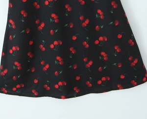 Detail of sweet cherry print on black fabric for a slim-fit halter neck mini dress