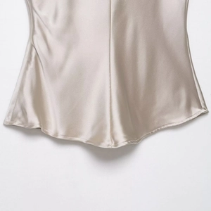 Champagne satin camisole with sweetheart neckline showing silky fabric and draped hem