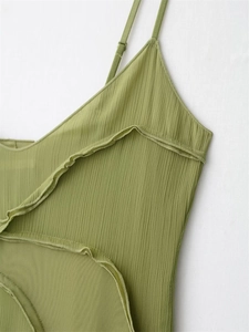Detail of green pleated dress featuring delicate ruffles and thin shoulder straps