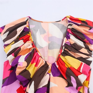 Detail of deep V-neckline with colorful geometric print and ruffled shoulder design
