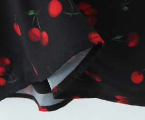 Macro detail of cherry print fabric showing neat stitching on a black mini dress
