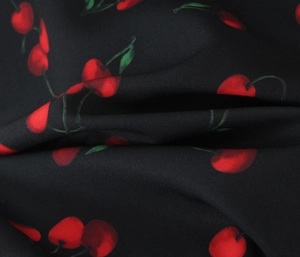 Close-up of black cherry print fabric with glossy silk texture and delicate drape