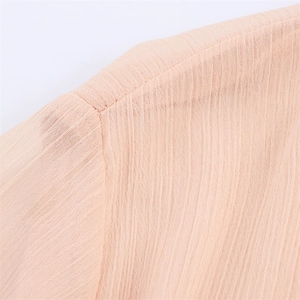 Detailed macro view of pleated fabric texture and shoulder seam on a beige pleated dress