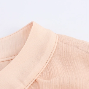 Detail shot of apricot pleated fabric with refined stitching on the neckline area