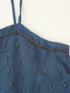 Detailed view of dark blue fabric with vertical silver beadwork and hand-crafted texture