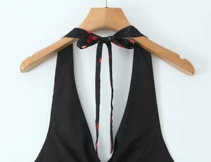 Detail of black halter dress featuring red cherry print ties and adjustable bow knot