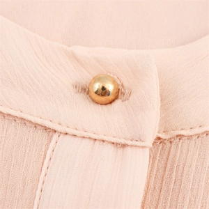 Macro shot of light pink pleated chiffon fabric with a round gold button detail