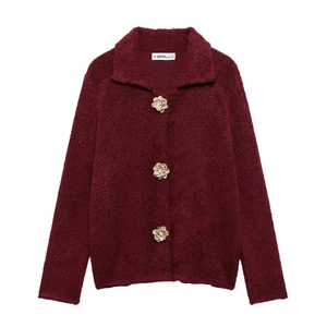 Détail d'un cardigan bordeaux en maille texturée avec des boutons dorés à fleurs