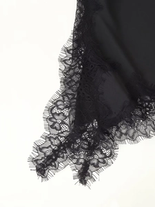 Detailed view of elegant black eyelash lace trim on smooth silk-like fabric texture