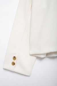 Détail de la manche d'une veste en laine ivoire avec boutons ambrés et tissu épais