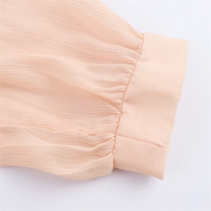 Detailed close-up of pleated apricot chiffon sleeve with smooth stitched cuff design
