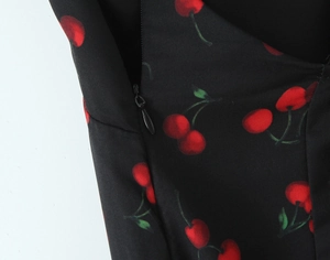Detail of invisible black zipper on black dress with red cherry print pattern