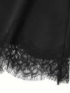 Detailed macro view of delicate eyelash lace trim on black satin fabric hemline
