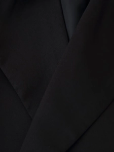 Gros plan du col cintré et du tissu tissé d'une veste de tailleur noire élégante